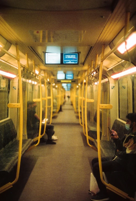 people are sitting on yellow seats in an empty subway car