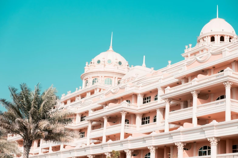 a pink building with palm trees surrounding it