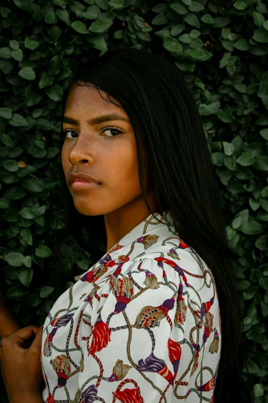 a person standing with her face covered by green bushes