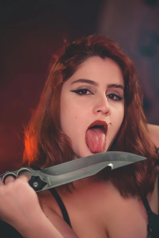 a woman pulling her tongue out with a very large knife
