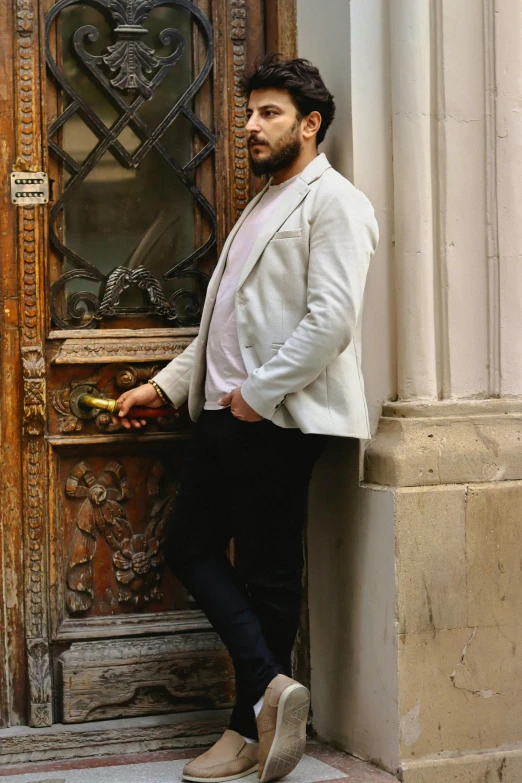 the man stands on the outside of an ornate wooden door