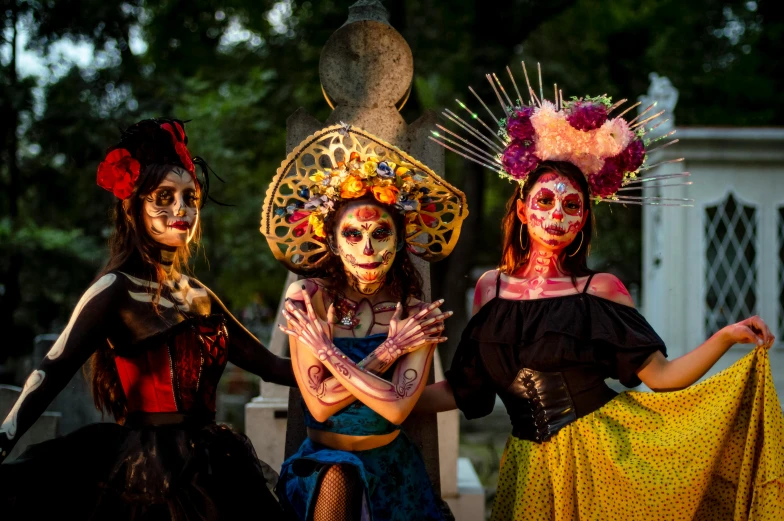 three women with painted skulls and decorations on their face