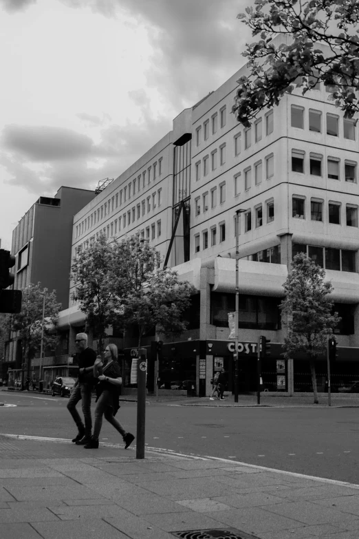 people walking and sitting on the side walk near some buildings