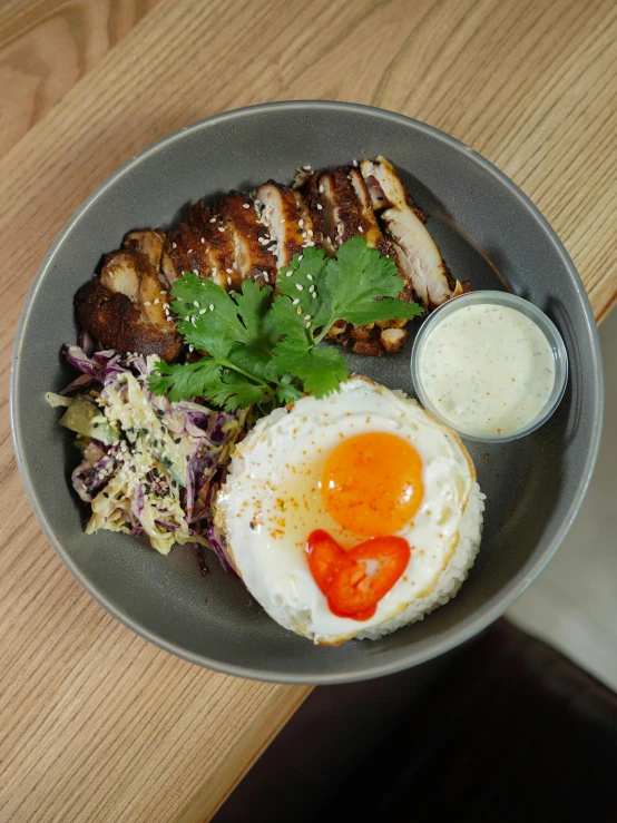 plate of food with pork, fried eggs, lettuce and some sauce