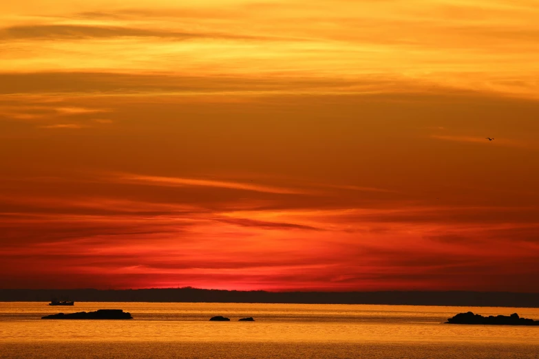 a sunset over the ocean with people in the water