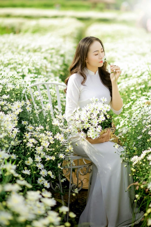 a young woman is holding flowers while sitting in a field