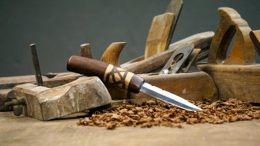 a large knife sits on top of wood