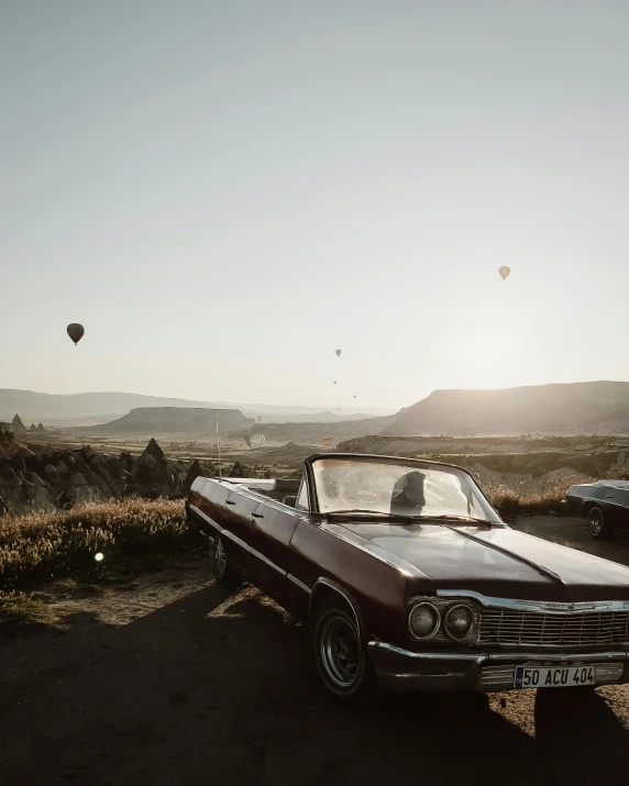 an old brown car is parked in front of some  air balloons