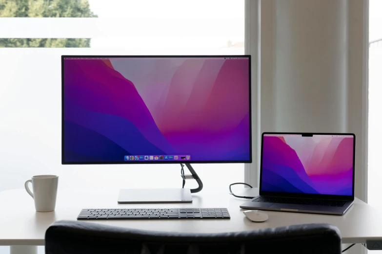 a desk with a keyboard, monitor and coffee cup sitting on it