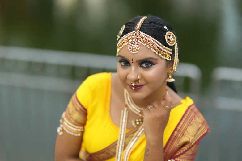 an indian woman in a yellow dress with dark eyebrows and traditional makeup