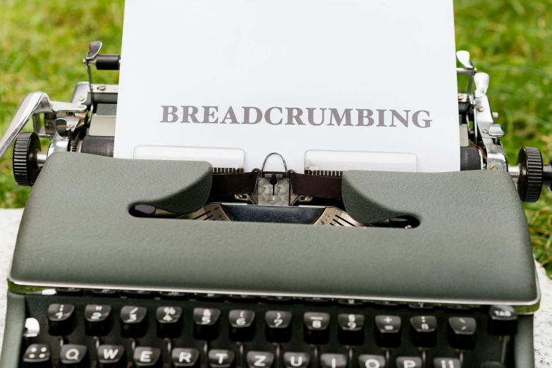 an old black typewriter with a sheet of paper reading breadcrumbing