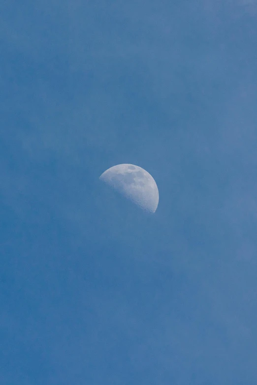 the moon is seen against the blue sky