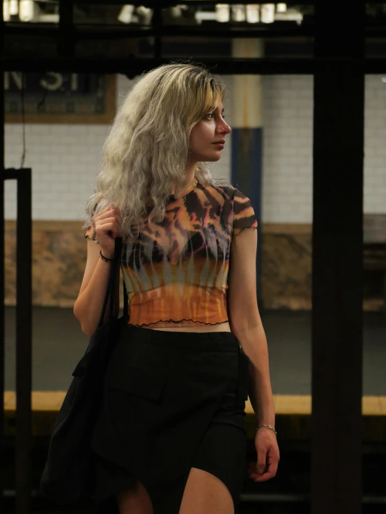 woman with long blonde hair walks on a subway platform