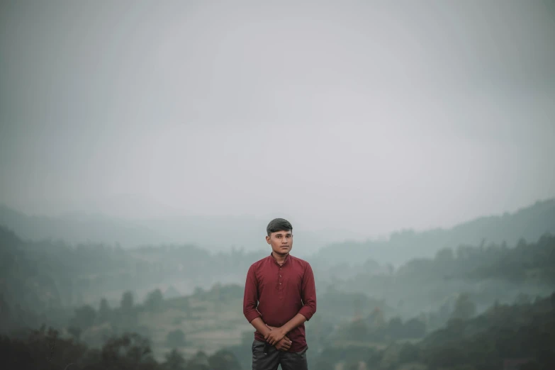 a man in a red shirt standing on top of a mountain