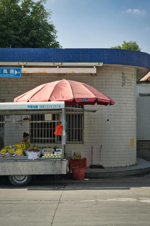 a fruit stand is set up in front of an umbrella