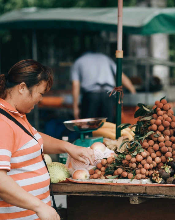 woman in striped shirt  vegetables at outdoor stand