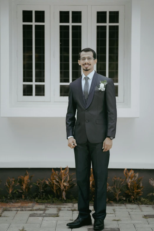 a smiling groom stands in front of a building