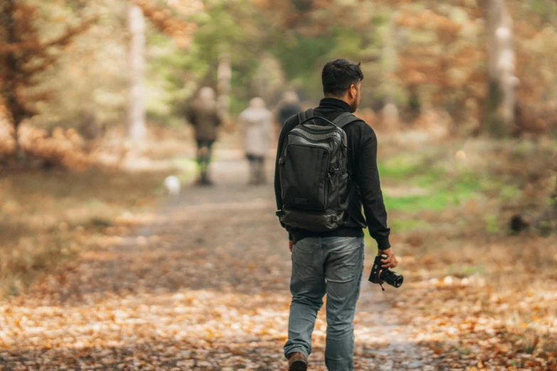 a man with a camera backpack walking on the street