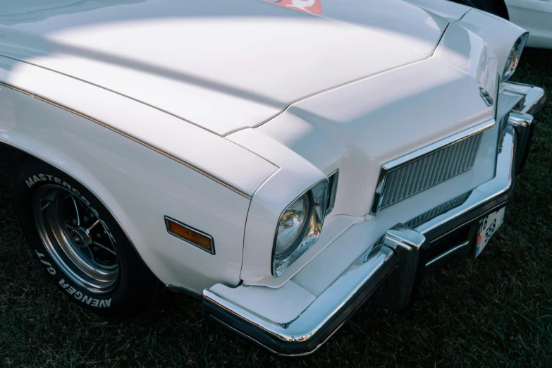 white classic car sitting on grass by a silver car