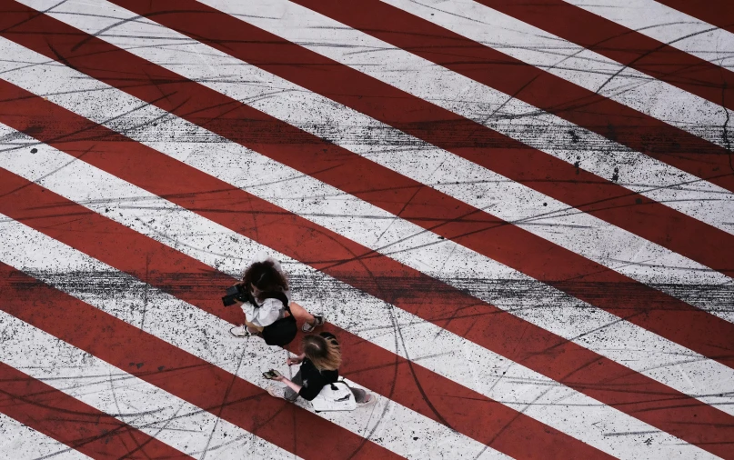 a woman walking across a red and white crosswalk