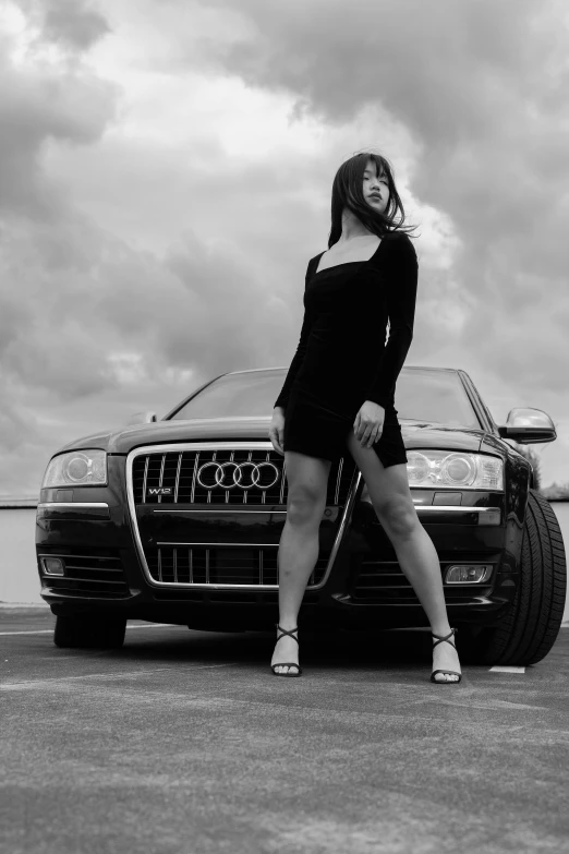 a black and white po of a woman leaning on a car
