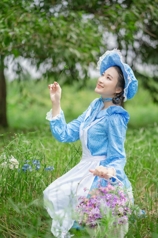 a woman dressed in a blue dress is sitting in the grass