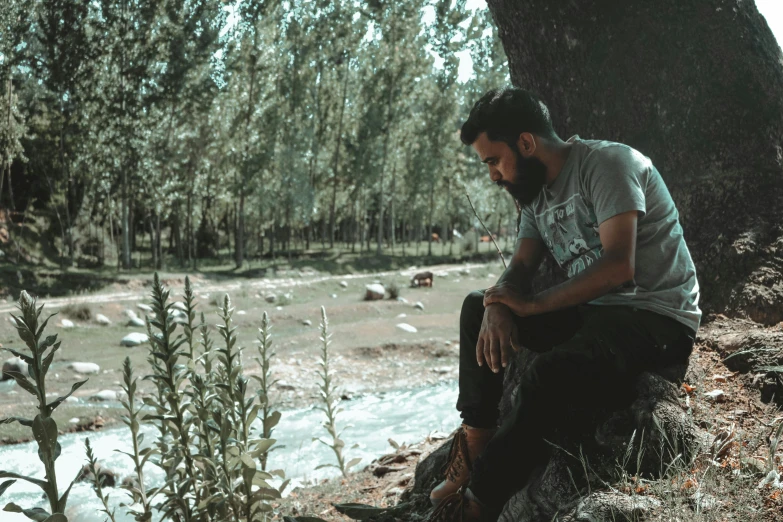 a man sits on a rock near a body of water