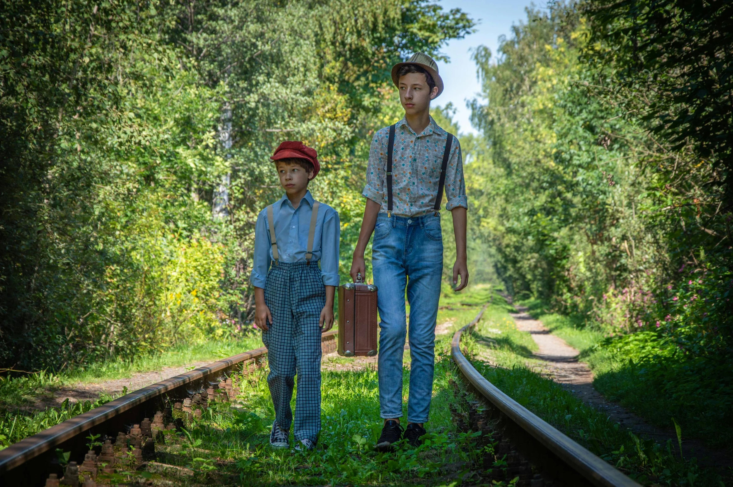 two young men standing on the railroad tracks