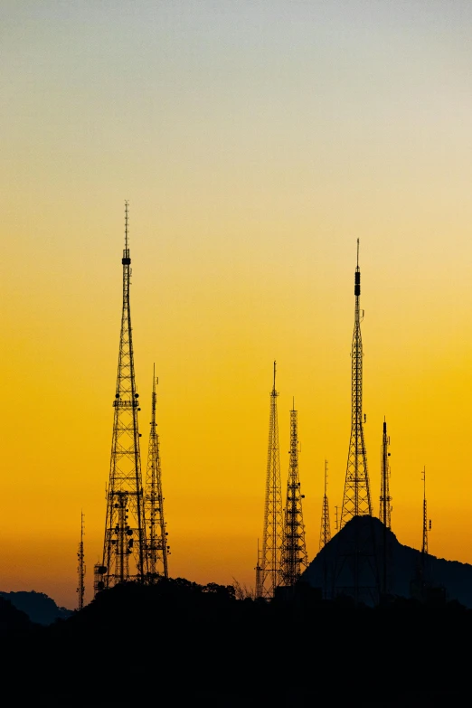 silhouette of many cell towers at sunset with one plane taking off