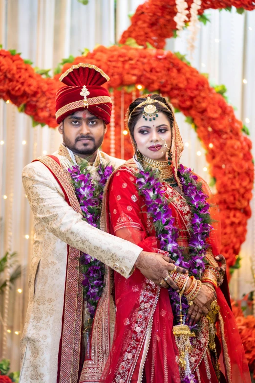 a newly married couple stands under a flower arrangement