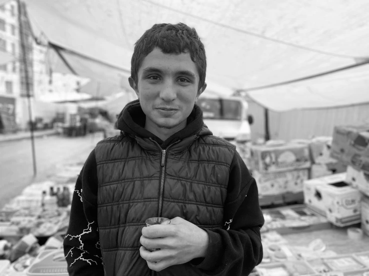 a young man in a black hooded jacket standing outdoors