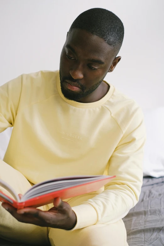 a man sitting on a bed holding an open book