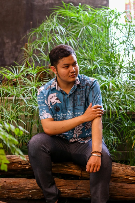 there is a man sitting on a log in front of some bamboo