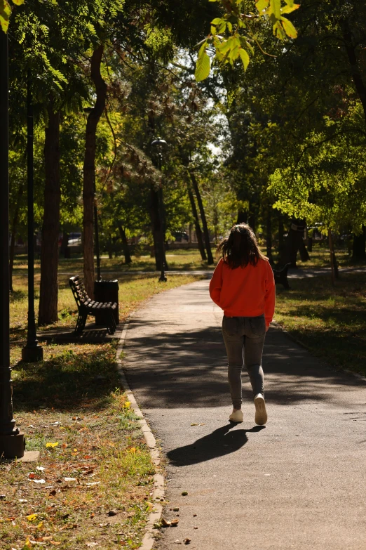 a woman in a red jacket walks down the sidewalk