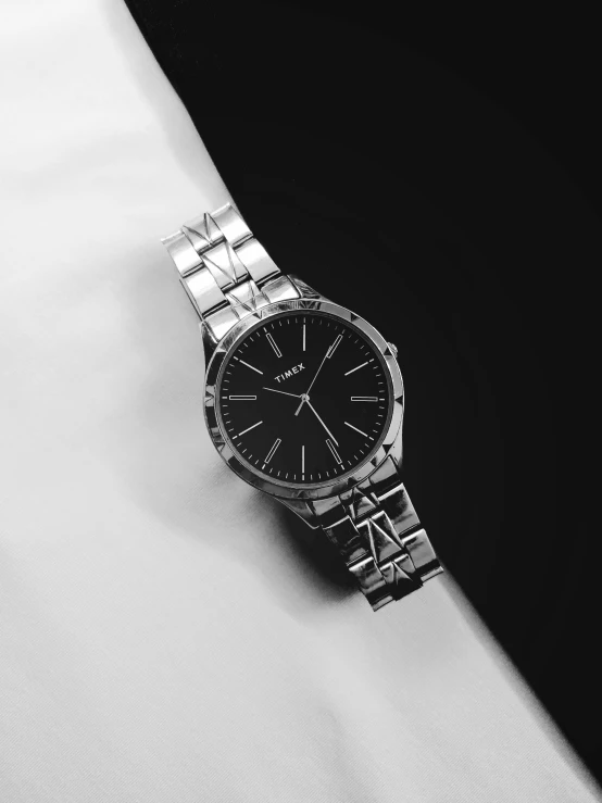 a silver watch with black dial on a black surface