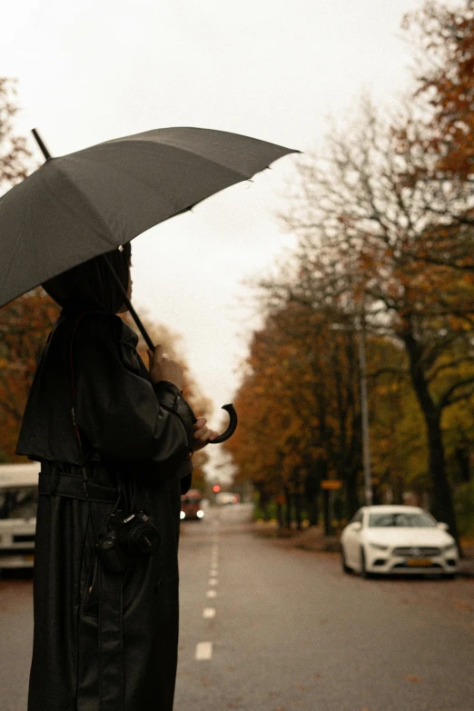 a woman standing on the side of a road holding an umbrella