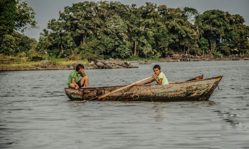 two people are in a wooden boat on a river