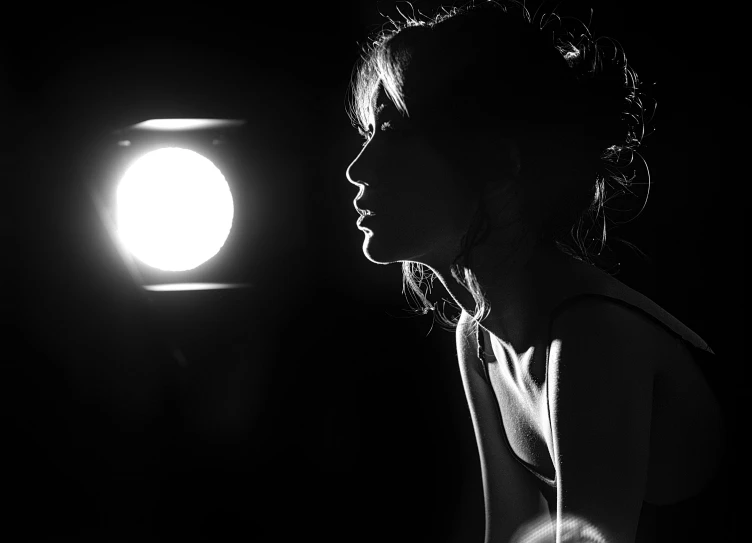 black and white pograph of woman profile against spotlight