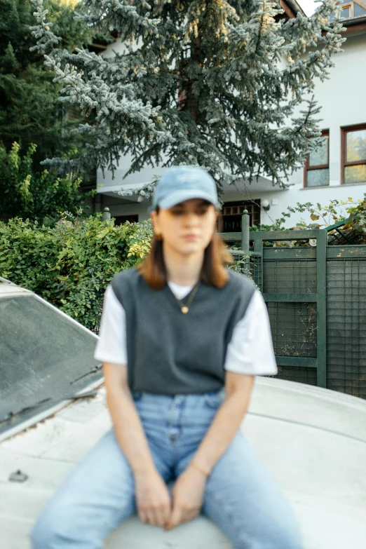 a woman sitting on top of a car with a tree behind her