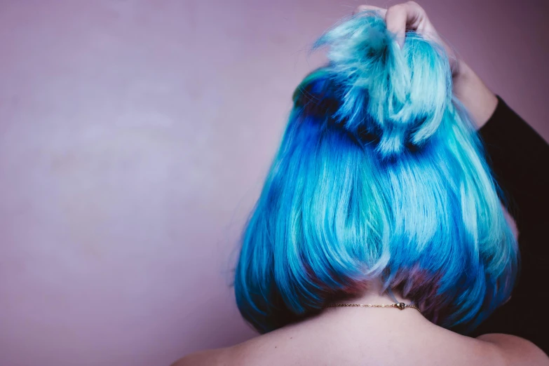 woman with pastel blue hair on head looking over shoulder