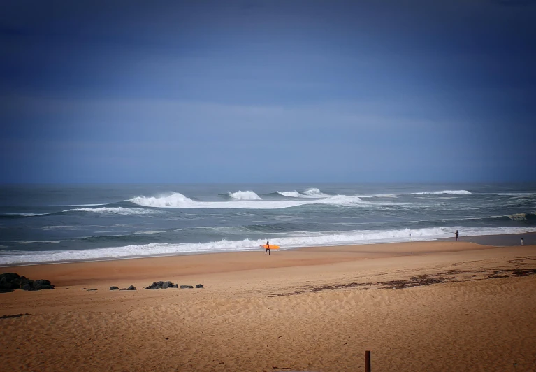 some people out on a beach while one has a surfboard