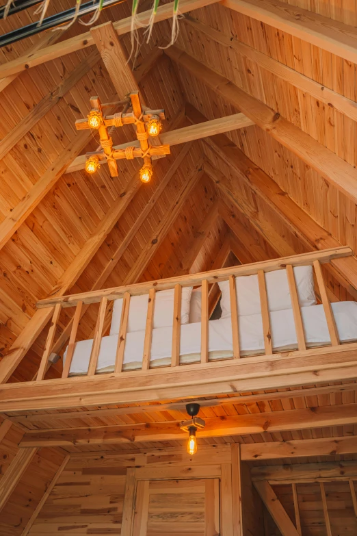 a loft with a wooden structure above looking towards the bedroom and balcony