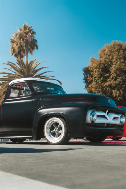 a black car parked on top of a parking lot next to palm trees