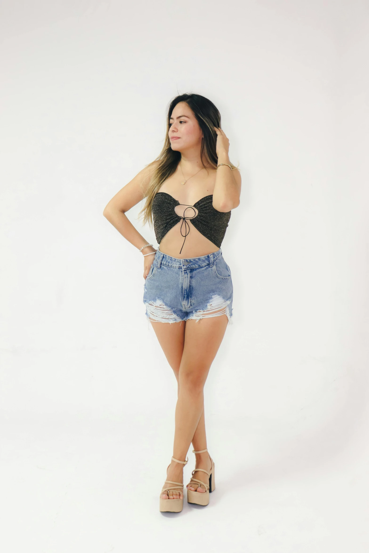 a woman in jean shorts and a black crop top is posing