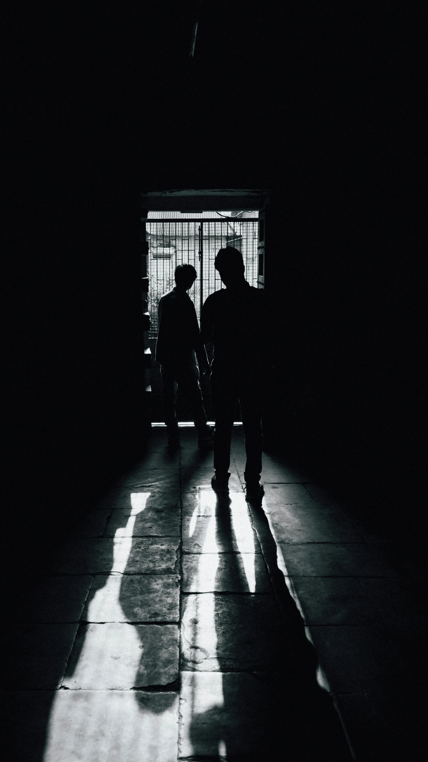 two people stand in the shadows of a  cell