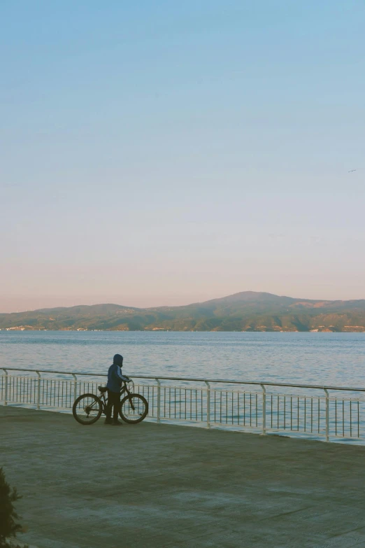 the man is sitting on a bike near a water