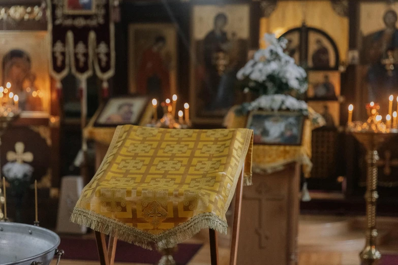 a yellow fabric and some wooden chairs in front of a wall with candles