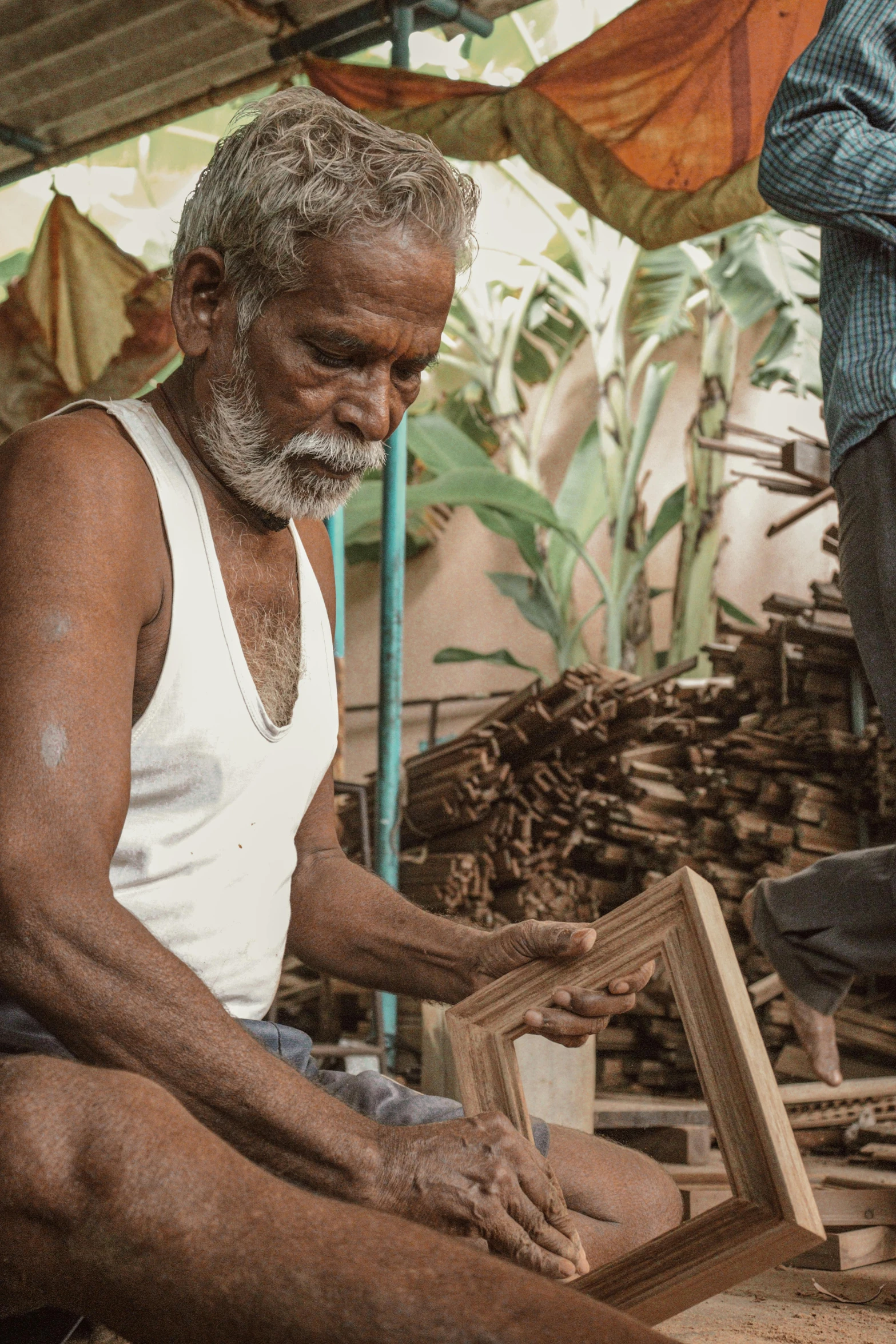 a man in white shirt sitting next to box of wood