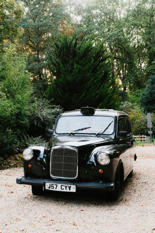 a classic car is parked on a gravel road