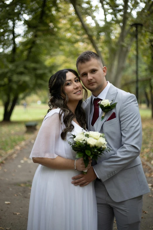 a beautiful bride and groom hugging in the park